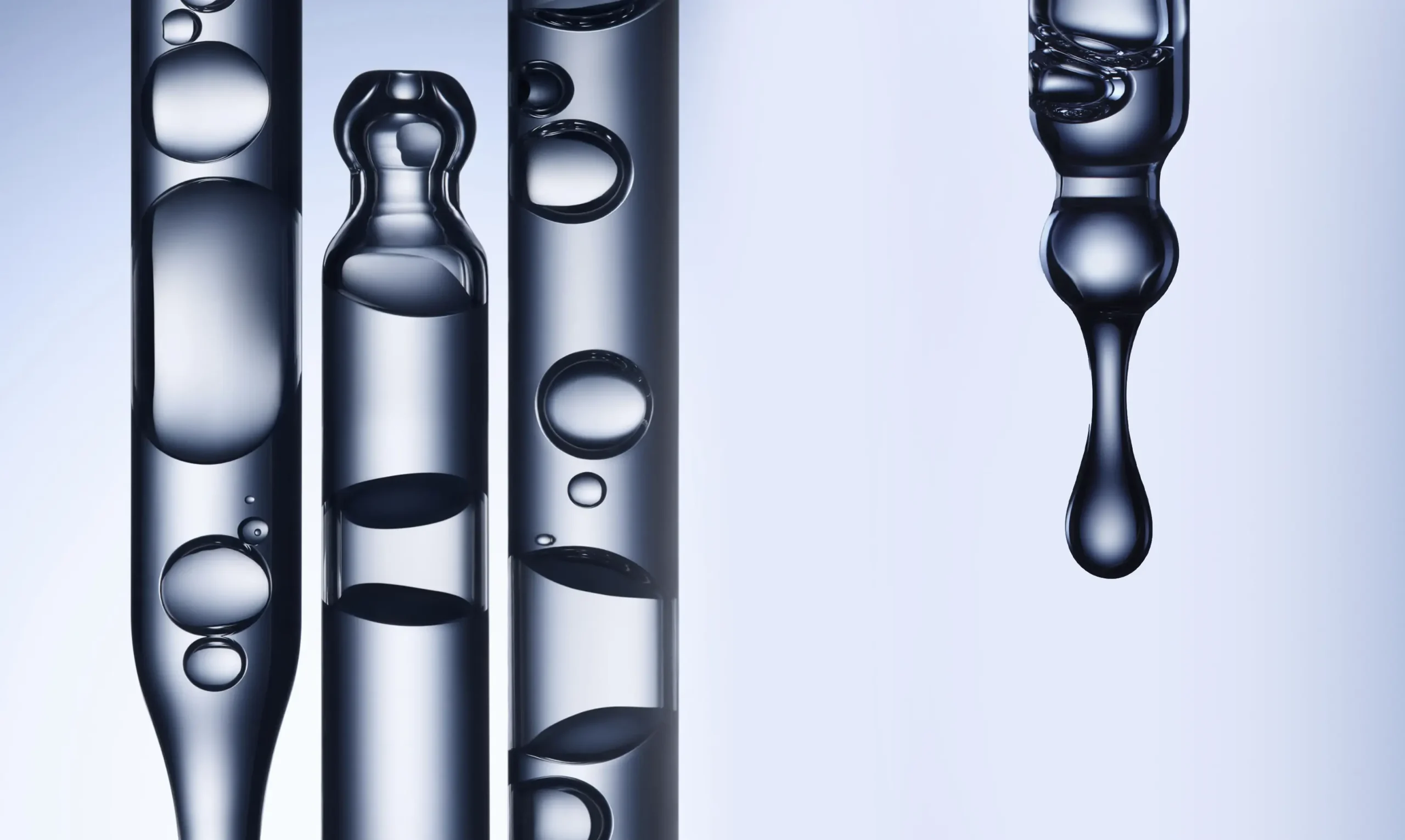 Close-up of transparent glass pipettes filled with liquid and air bubbles, with one drop forming at the tip of a pipette on the right, against a light blue background.