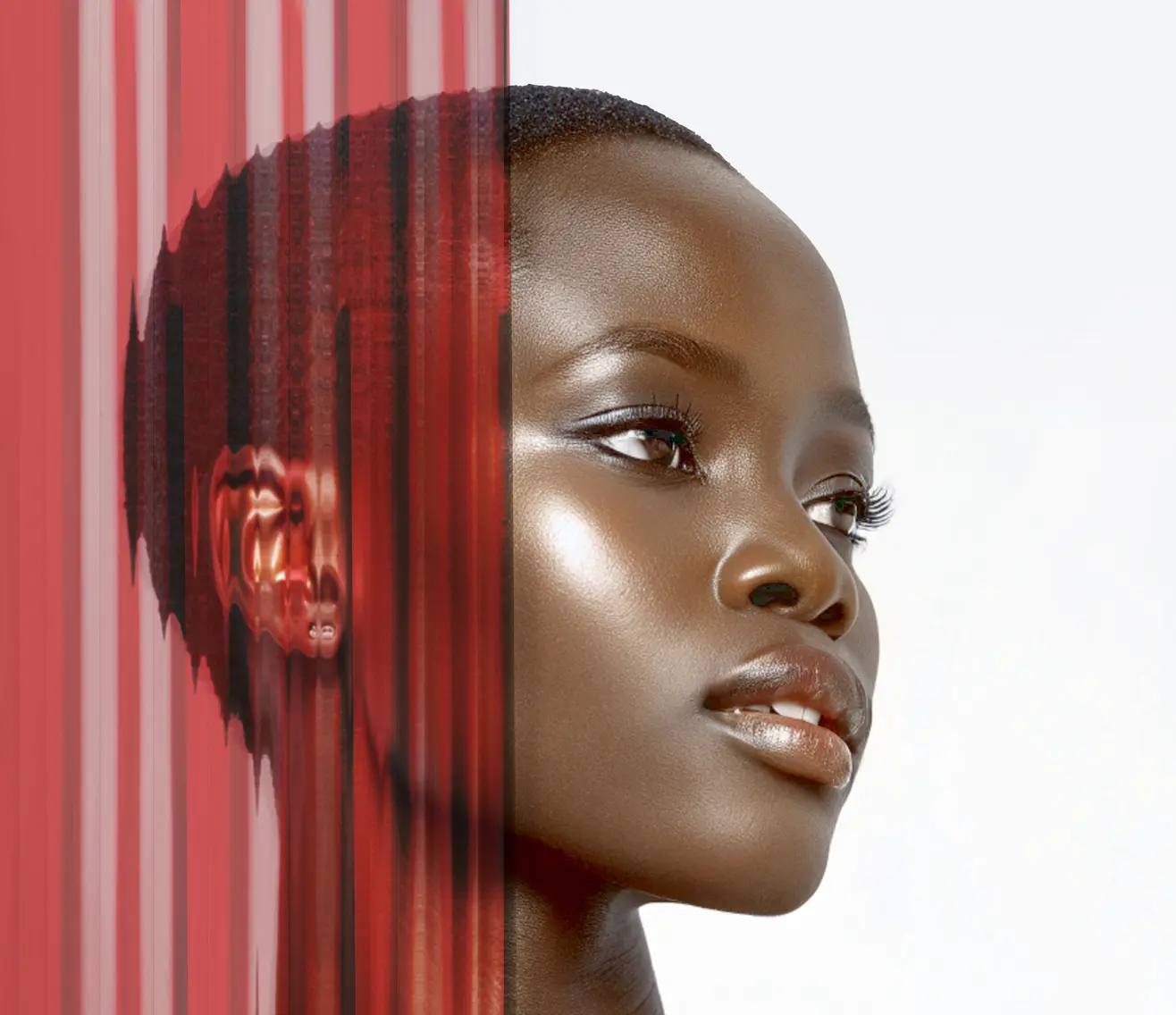 A woman with smooth, dark skin gazes confidently to the right. The left side of her face is blurred by vertical red distortion, creating an artistic, abstract effect. The background is light gray.