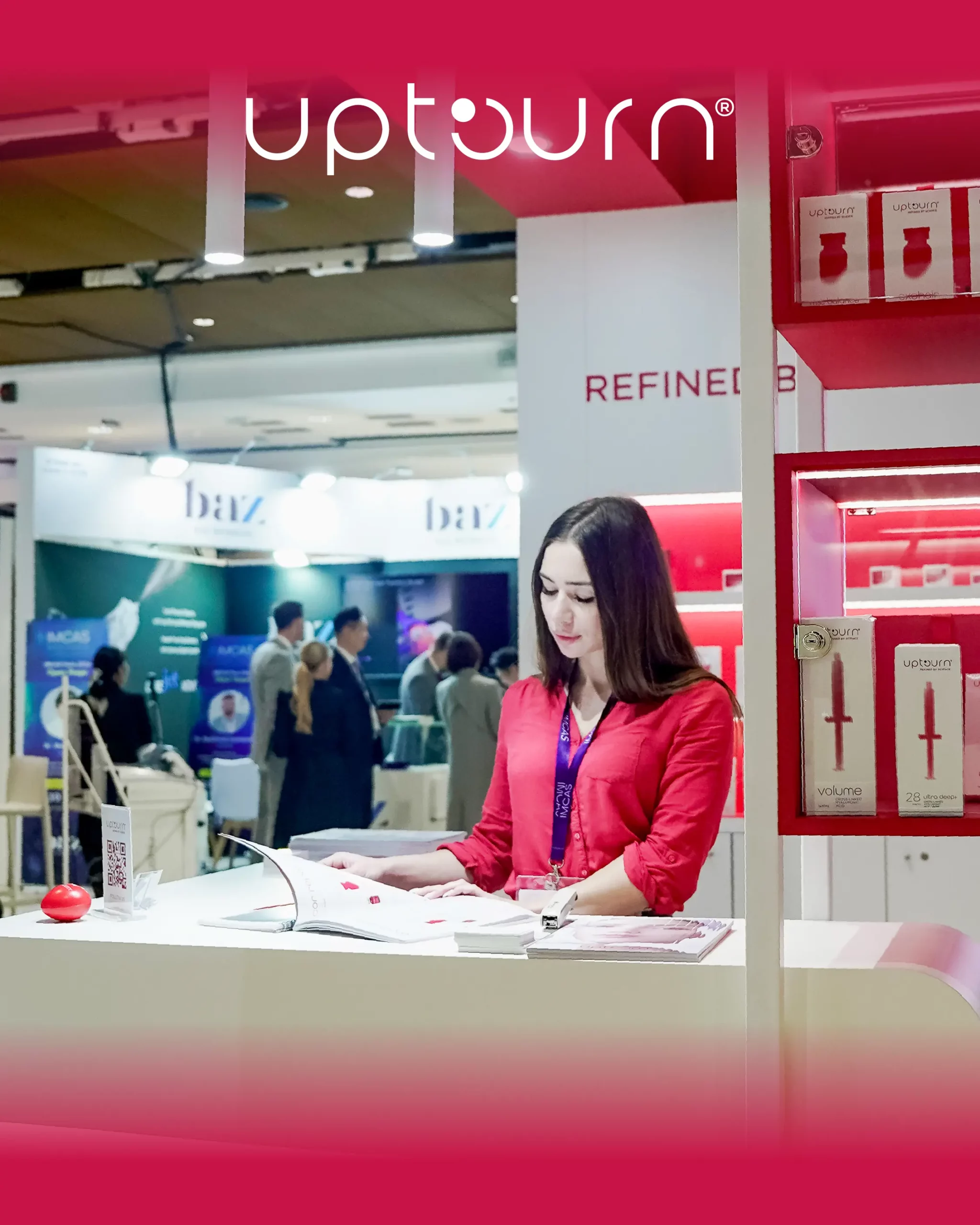 A woman in a red shirt stands at a booth, reading a brochure. The booth displays "upturn" branding and kitchen knives. People and other booths are visible in the background at an indoor event or exhibition.